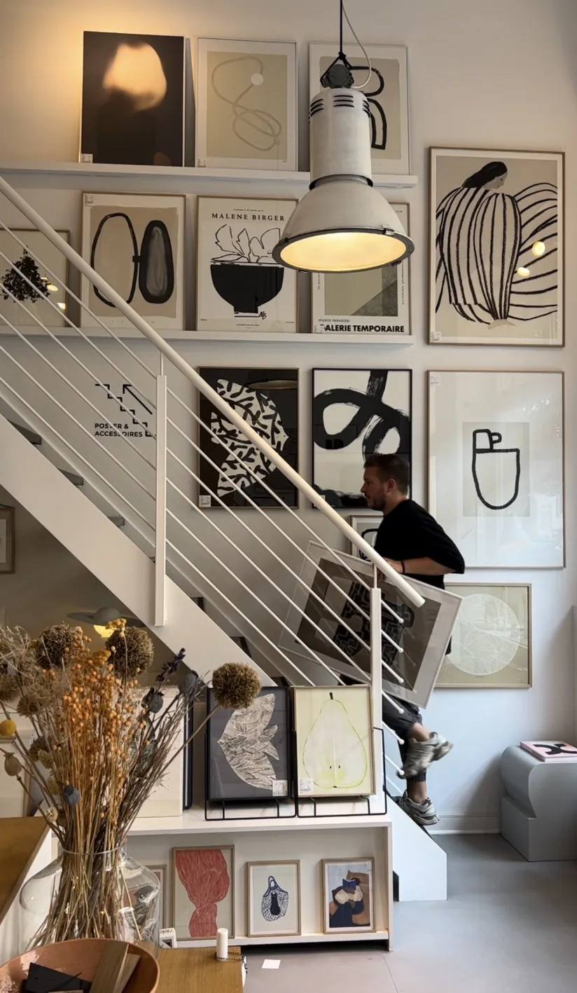 Vincent Templin, Art Director und Human Design Mentor des Holistic Playground, trägt einen gerahmten Kunstdruck durch einen Plakatladen