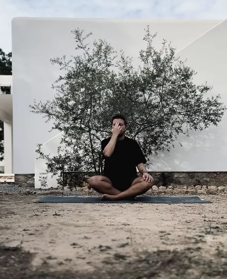 Vincent Templin, Art Director und Human Design Mentor des Holistic Playground, sitzend auf einer Yogamatte vor einem Olivenbaum